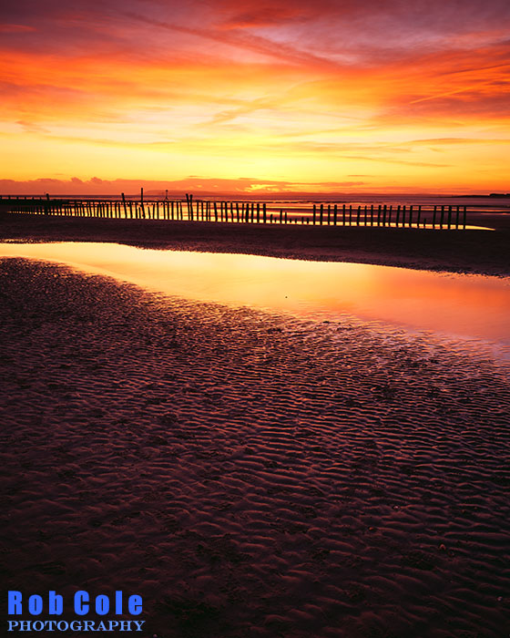 The sun sets behind a bank of cloud at West Wittering beach